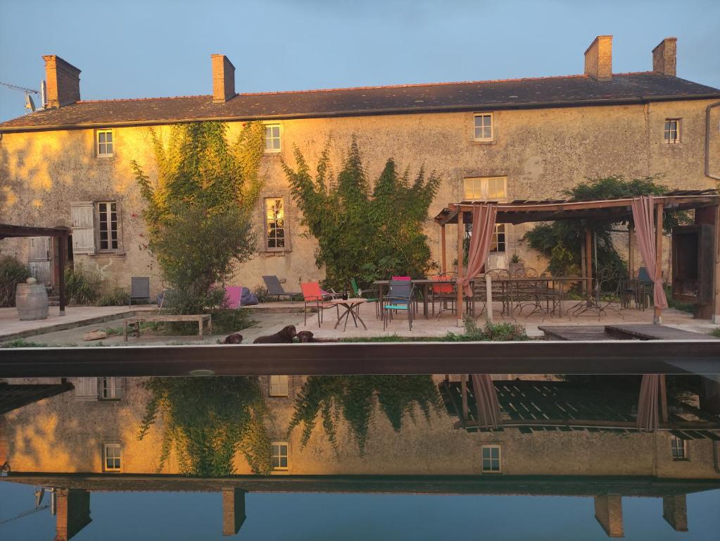 a house with a reflection in the water at Le Manoir de Gâtines in Tigné