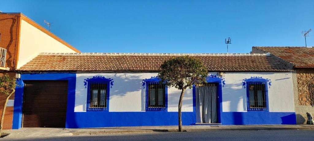 une maison bleue et blanche avec un arbre à l'avant dans l'établissement Casa rural La Golondrina, à Villarta de San Juan