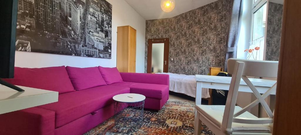 ein Wohnzimmer mit einem lila Sofa und einem Bett in der Unterkunft Büdchen am Rathaus-Parkplatz-Bett und Schlafcouch-EG-NETFLIX- in Oberhausen