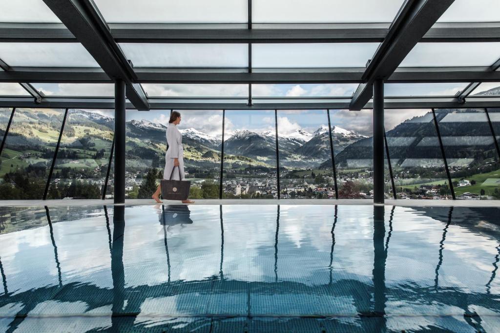 a woman with a suitcase standing in front of a swimming pool at Lebenberg Schlosshotel-Kitzbühel in Kitzbühel