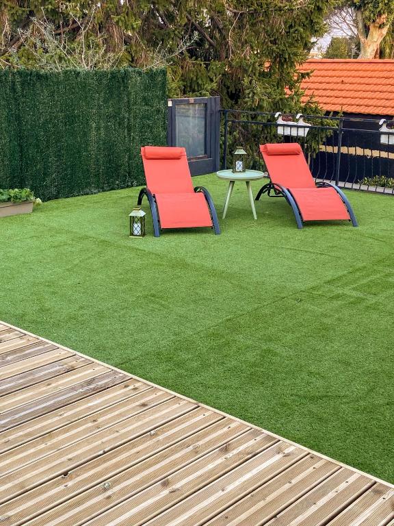 2 chaises rouges et une table sur une pelouse dans l'établissement Villa à Golfe Juan, à Vallauris