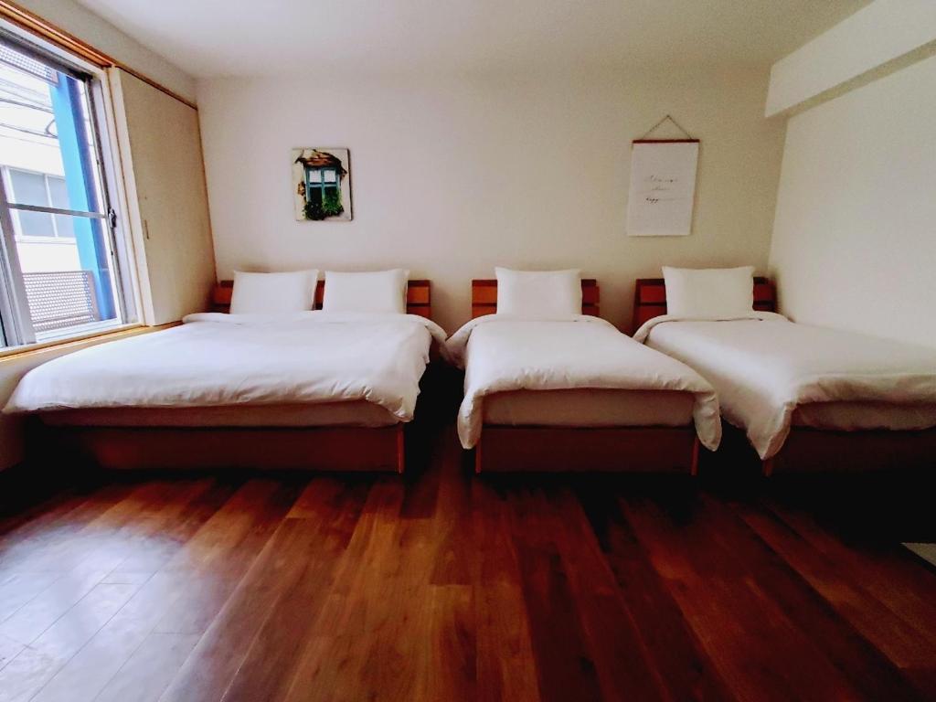 two beds in a room with wooden floors at Rooms in Tokyo