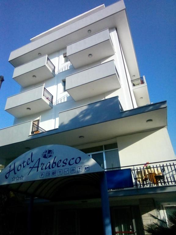 a large white building with a sign in front of it at Hotel Arabesco in Rimini