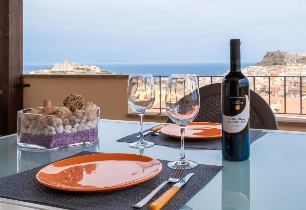 un tavolo con due bicchieri e una bottiglia di vino di CASTELSARDO- Elegante Appartamento vista Mare a Castelsardo