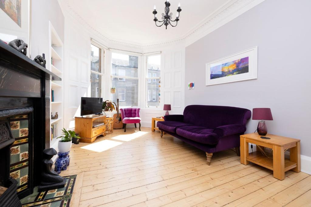 a living room with a purple couch and a tv at JOIVY Gorgeous 1-bed flat with a shared garden in Edinburgh