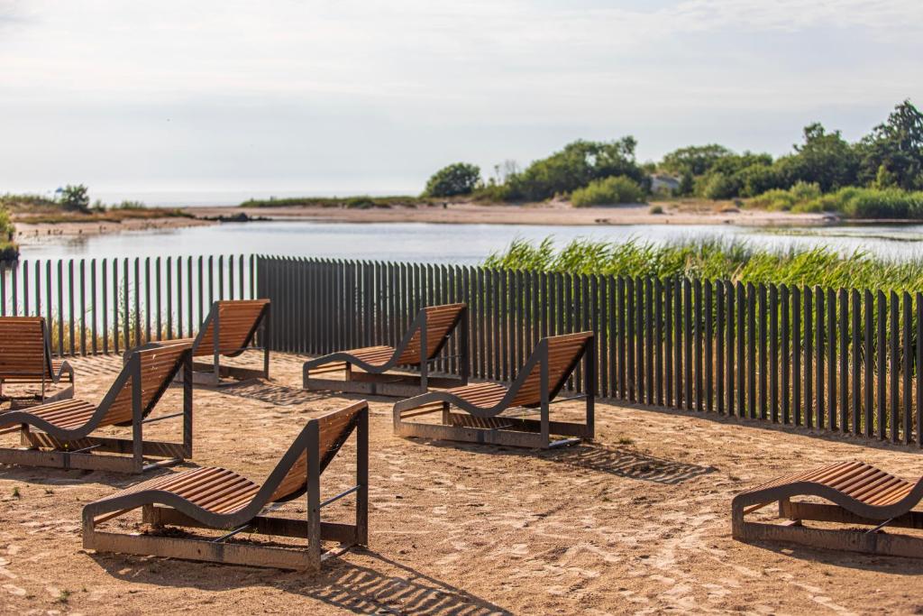 a group of chairs sitting in the sand near a body of water at THE BEST OF ŠVENTOSIOS VARTAI, By Cohost in Šventoji