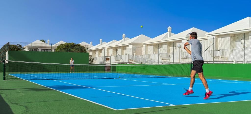 a man swinging a tennis racket on a tennis court at H10 Ocean Suites in Corralejo