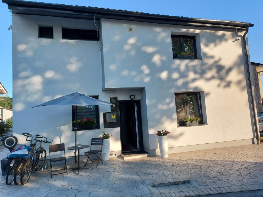 a white house with a table and chairs and an umbrella at Vila Maria băile felix in Baile Felix