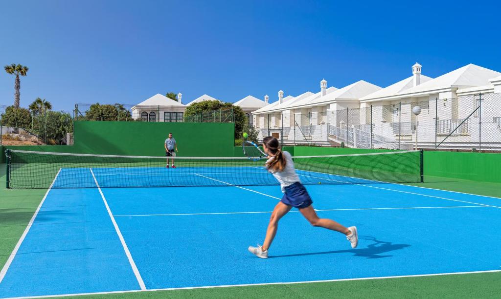 two people playing tennis on a tennis court at H10 Ocean Suites in Corralejo