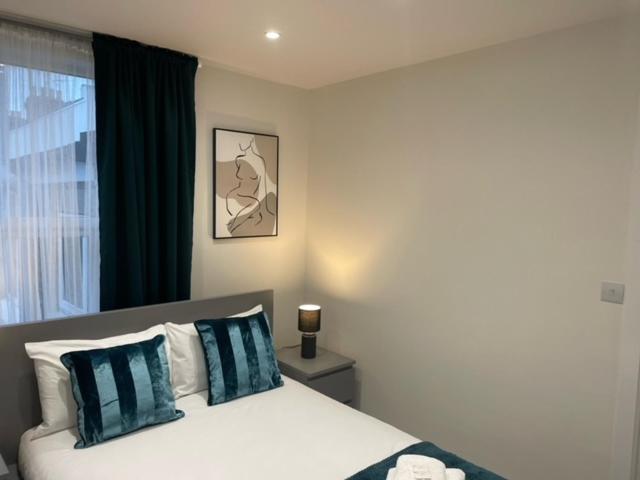 een slaapkamer met een bed met blauwe en witte kussens bij 2 Bedroom serviced apartment in Londen