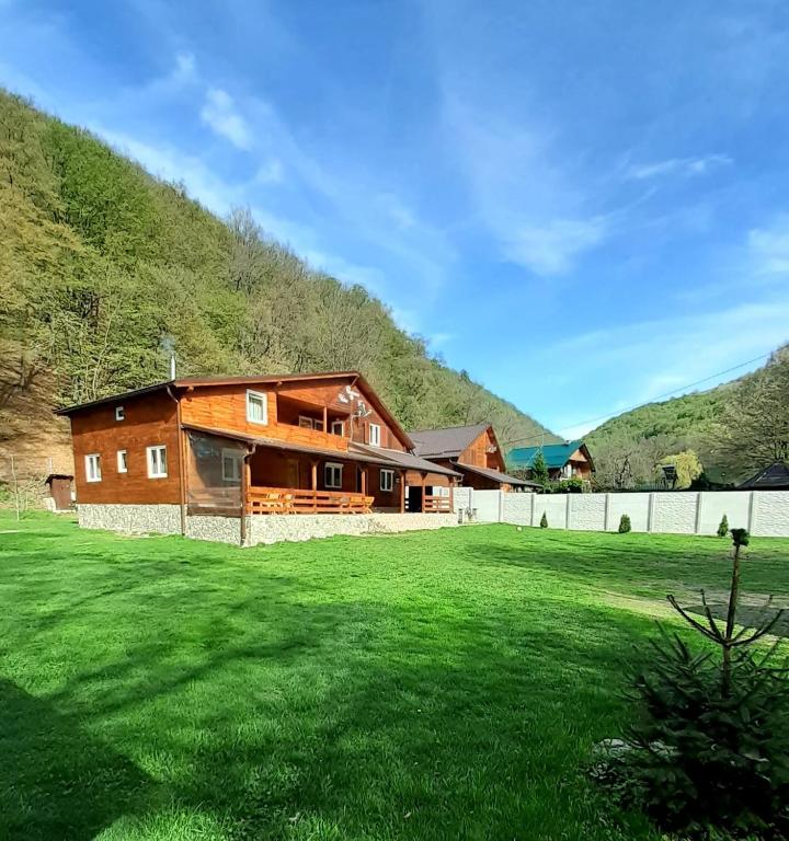 a large house with a grass field in front of it at Pensiunea Valea Tonii in Strungari