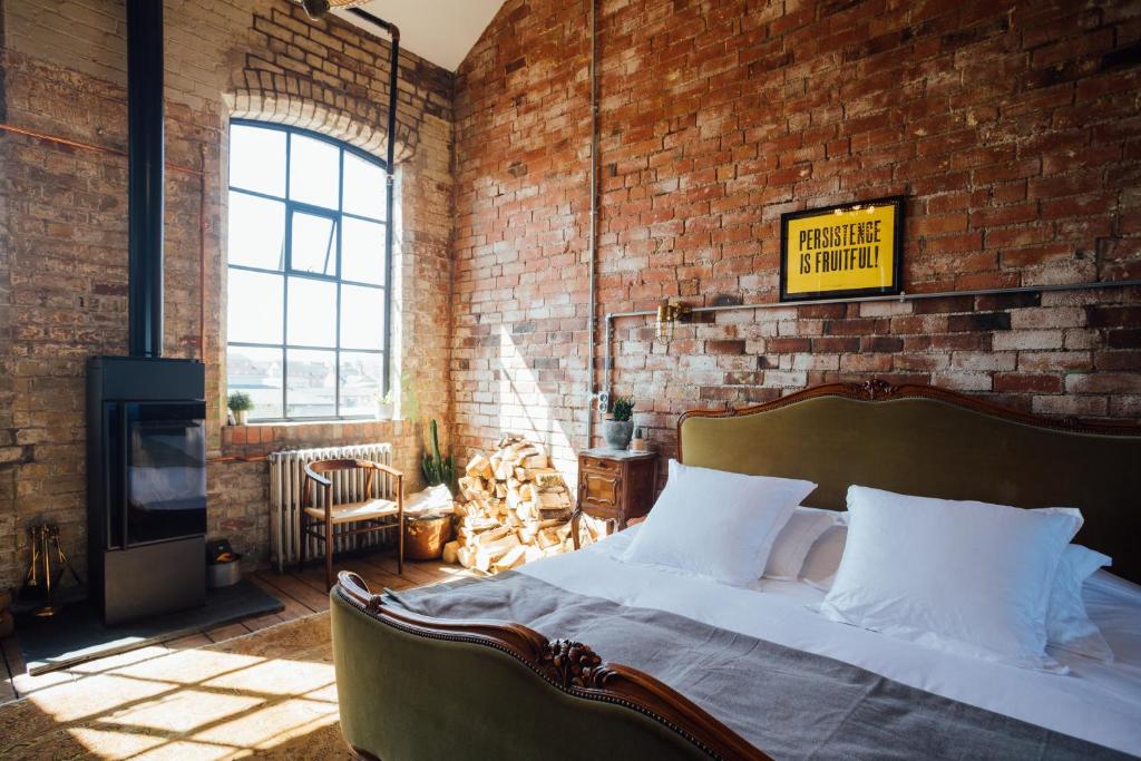 a bedroom with a bed and a brick wall at Destinesia Jason Works in Loughborough