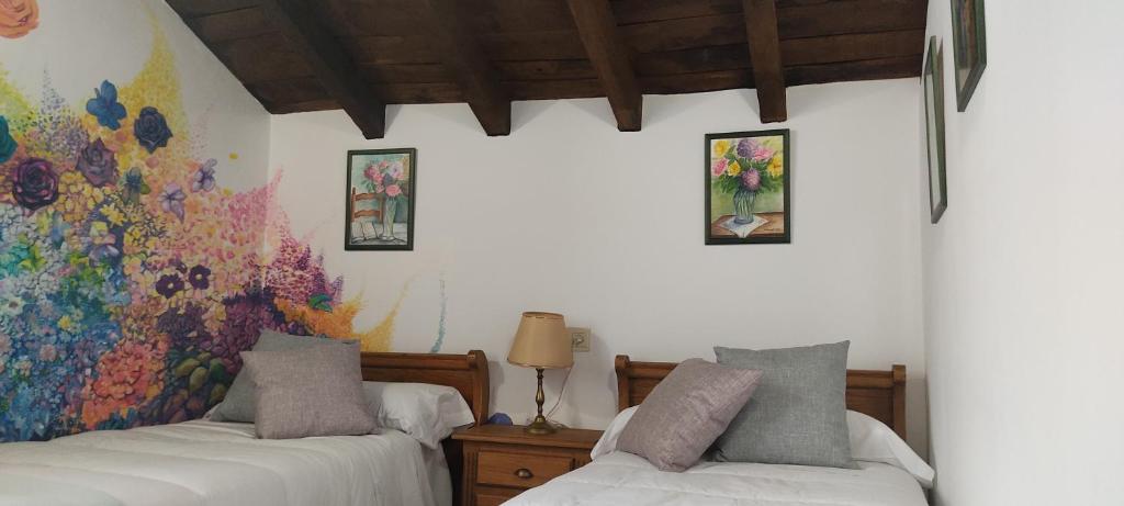 a bedroom with two beds and a painting on the wall at Hostal Mendaurpe in Ituren