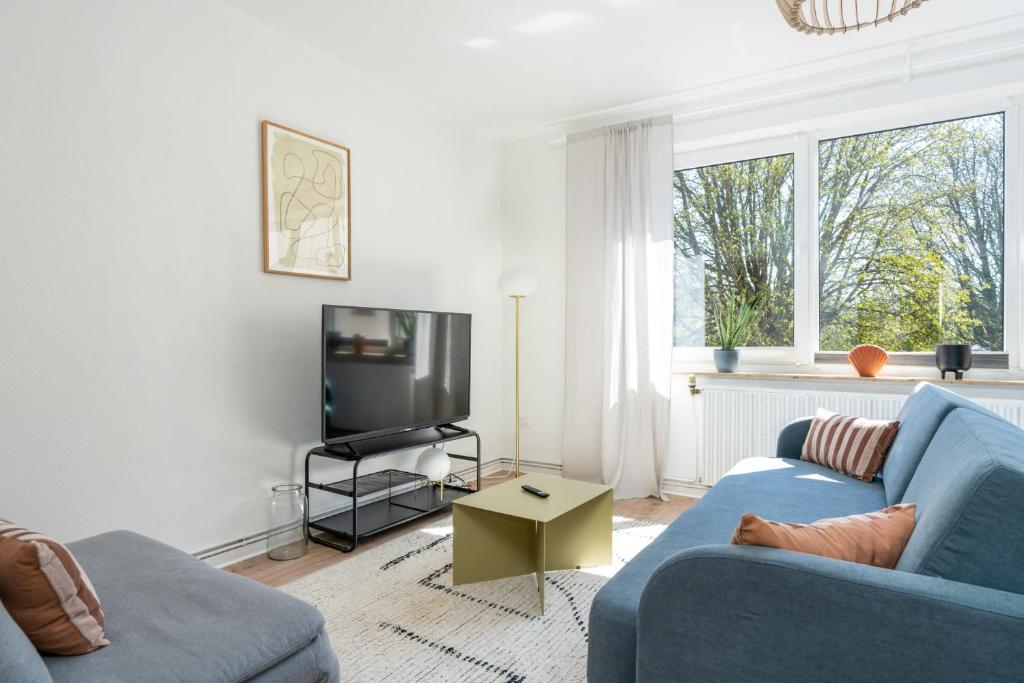 a living room with a blue couch and a tv at FLATLIGHT - Shiny Apartment - Balcony - Central - Kitchen in Hildesheim