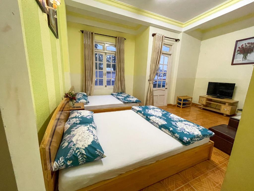 a bedroom with two beds and a television in it at CSLTDL Quỳnh Nhi in Da Lat