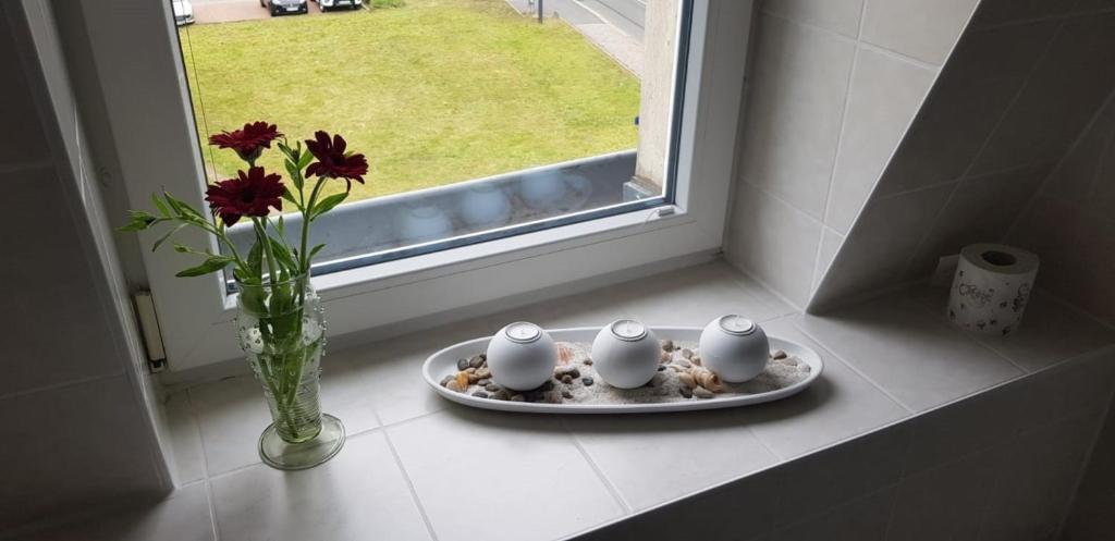 eine Vase mit Blumen und einen Teller mit drei Kerzen an einem Fenster in der Unterkunft An den Elbwiesen in Dresden