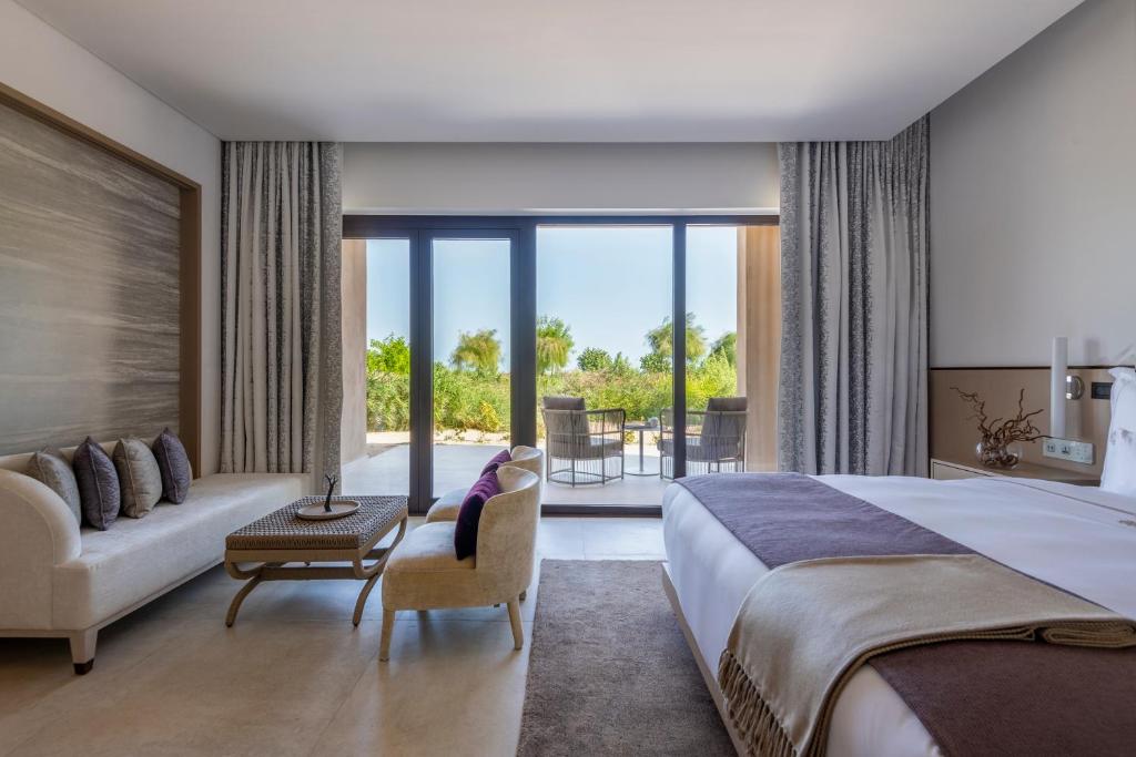 - une chambre avec un grand lit et un salon dans l'établissement Zulal Wellness Resort by Chiva-Som, à Ar Ruʼays