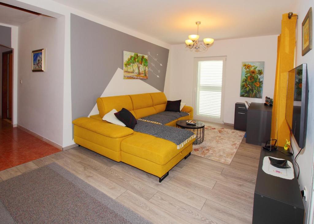 uma sala de estar com um sofá amarelo e uma televisão em Apartment Marita em Cilipi