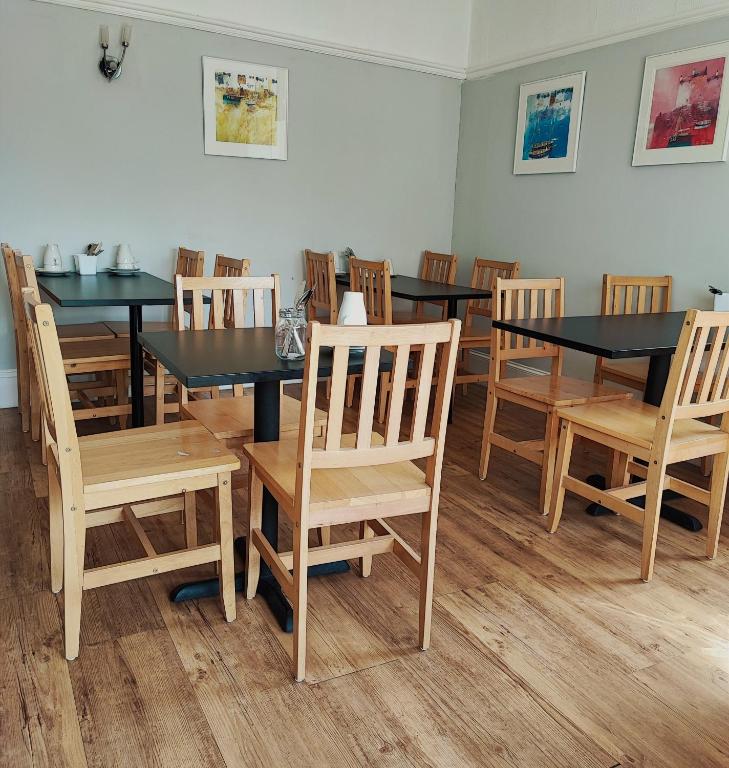 a dining room with black tables and wooden chairs at St Breca in Newquay