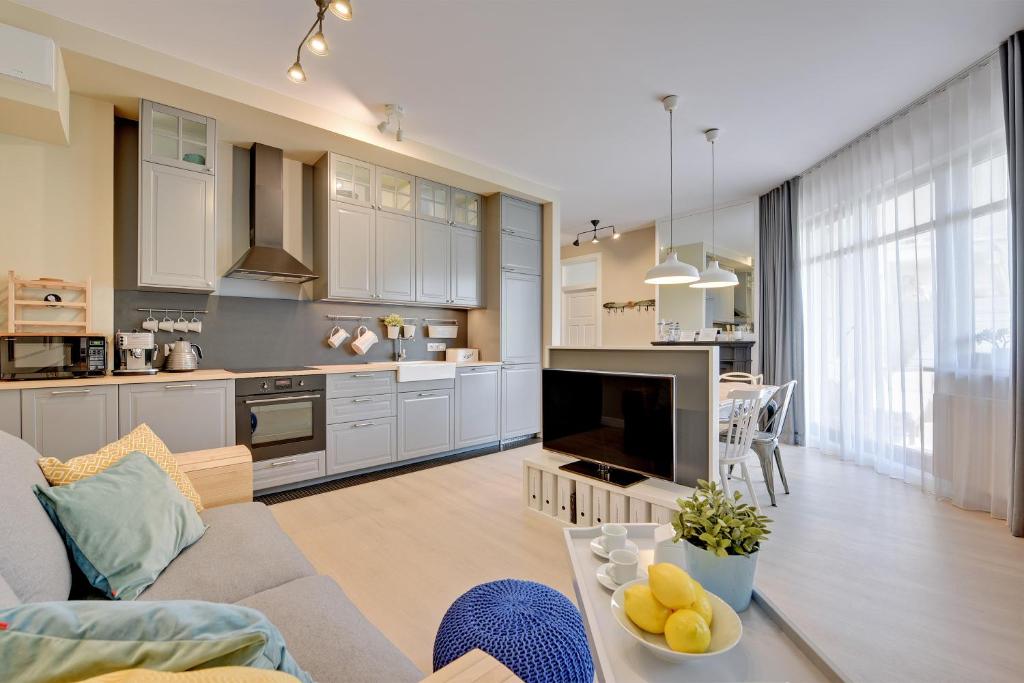 a kitchen and living room with a couch and a tv at Dom & House Apartment Neptun Park Comfort in Gdańsk