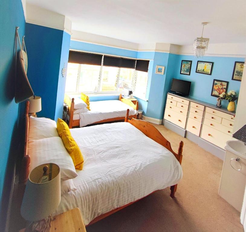 two beds in a bedroom with blue walls at St Breca in Newquay