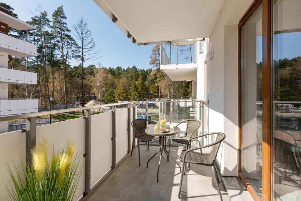 Sunny balcony with small round table, four wicker chairs and drink pitcher.