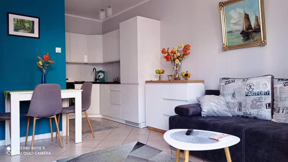 a living room with a couch and a table and a kitchen at Marina Apartments in Kołobrzeg