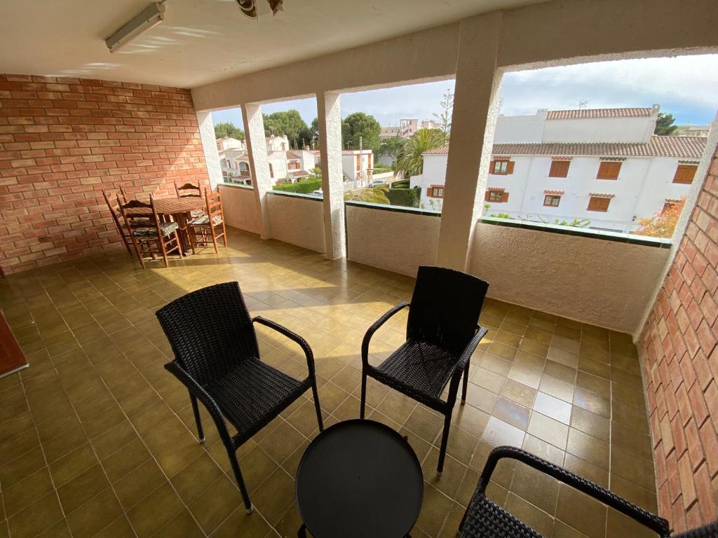 dwa krzesła i stół na balkonie z oknami w obiekcie Apartamentos Neptuno Altamar w mieście Alcossebre