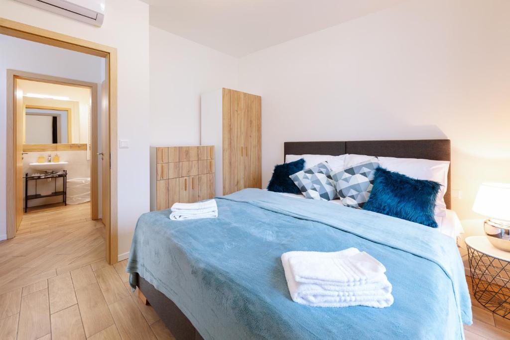 a bedroom with a blue bed with towels on it at Folimanka Apartments in Prague