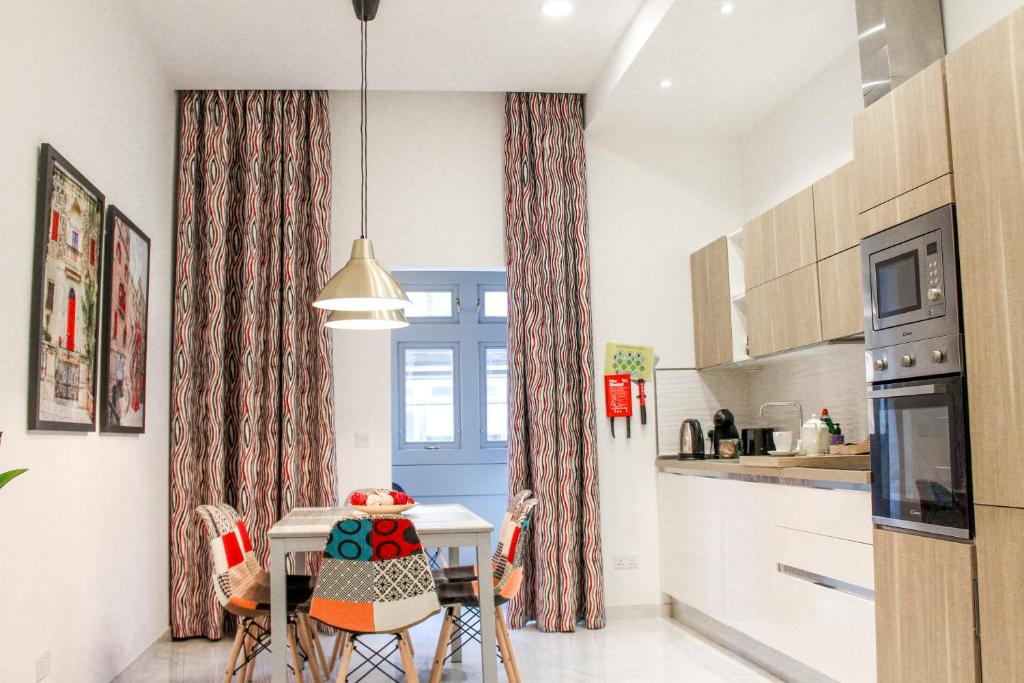 uma cozinha com uma mesa e cadeiras numa cozinha em QLiving Central New Apartments Gzira Sliema Promenade em Il-Gżira