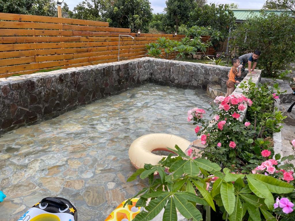 a man standing in a pool of water with flowers at 寧靜的家14人Villa獨立設施包棟戲水池烤肉區麻將廚房私人停車場 in Hengchun South Gate