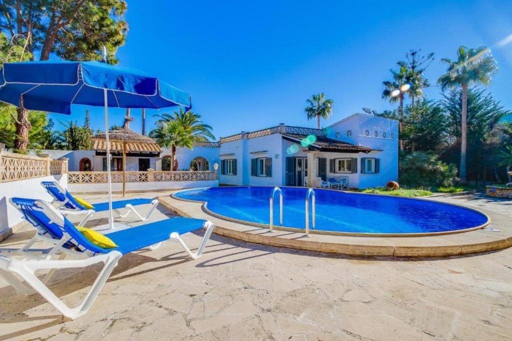 una piscina con due sedie a sdraio e una casa di Villa Julieta a Cala Murada