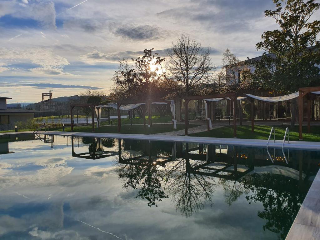 Hotel rural Finca Vivaldi Nature & Spa في San Miguel de las Dueñas: مسبح مع وضع الشمس في الخلفية
