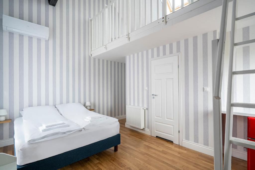 a bedroom with a white bed and a staircase at W Starym Porcie - pokój z widokiem na Zalew Wiślany balkonem i antresolą in Krynica Morska