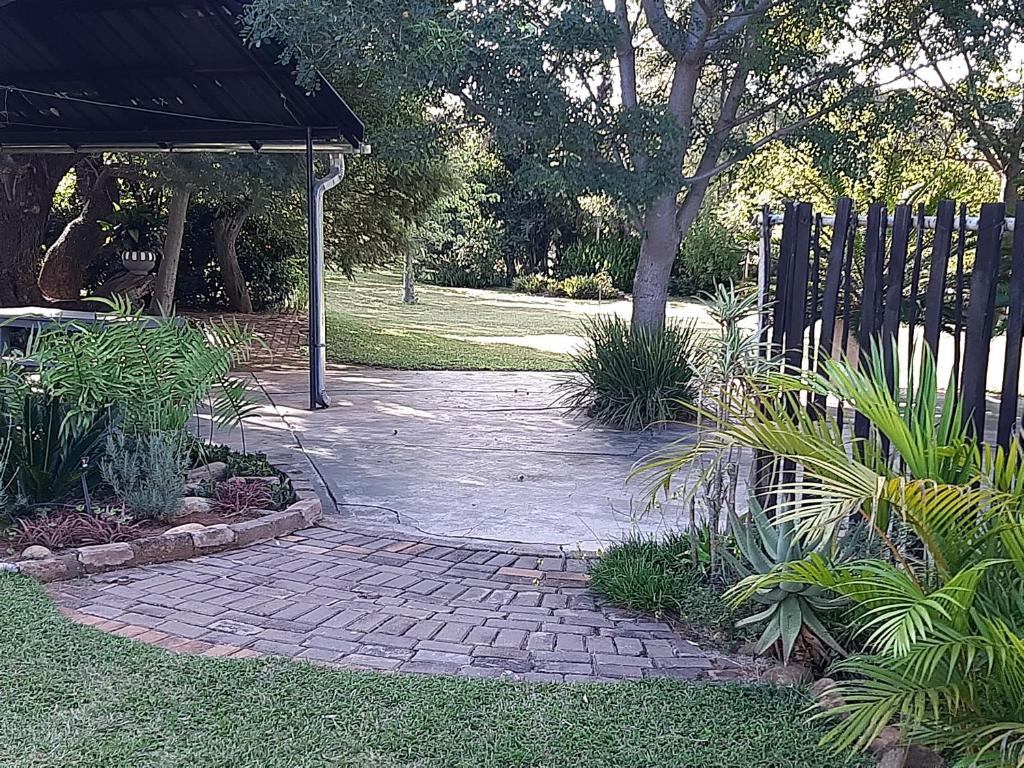 Una pasarela de ladrillo en un jardín con una valla en In Da Bush, en Modimolle