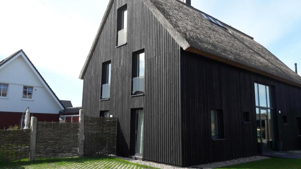 a black house with a thatched roof at Ferienhaus Niege Schüün in Born