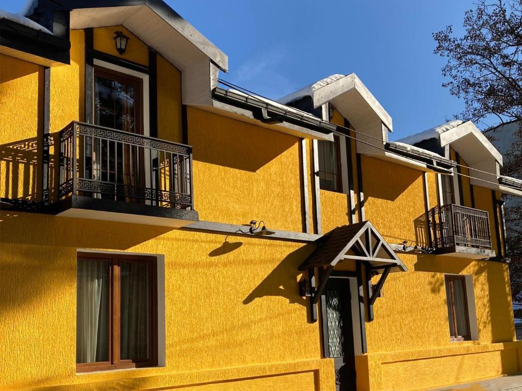 un edificio amarillo con 2 balcones en un lateral en Borjomi Yellow Hotel en Borjomi