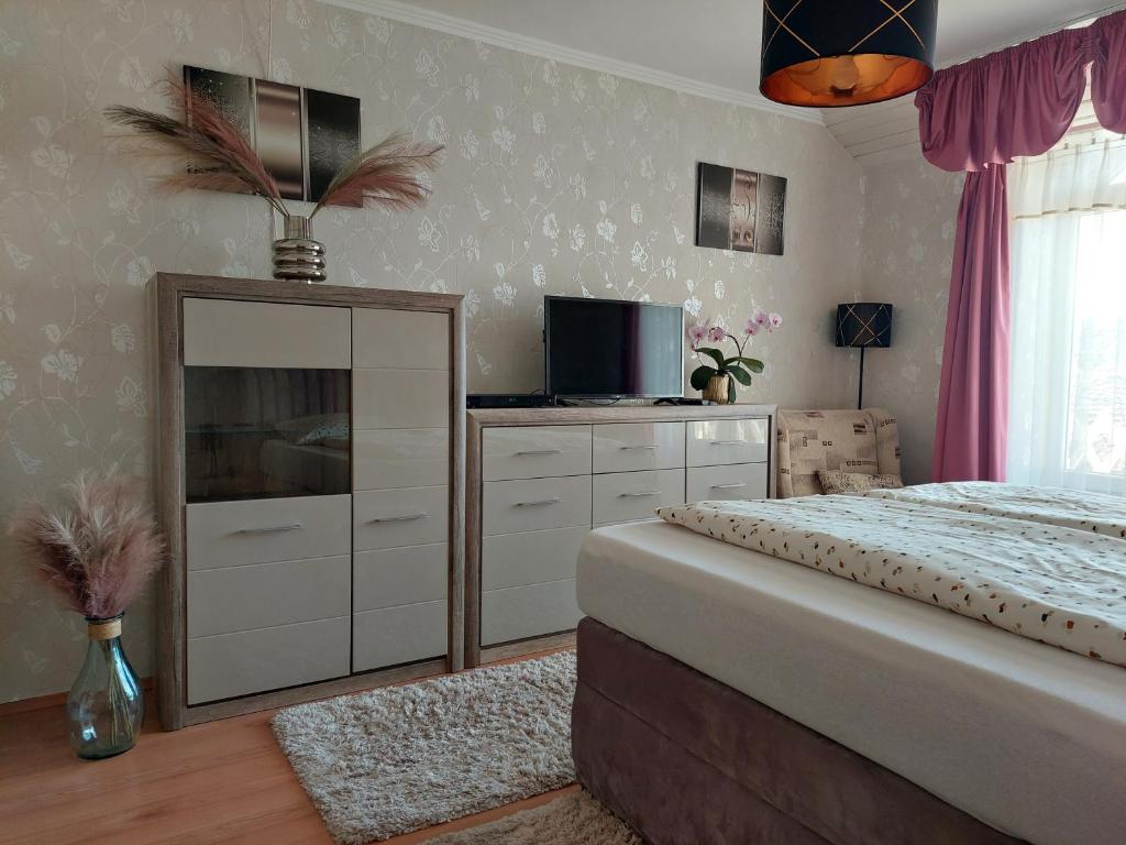 ein Schlafzimmer mit einem Bett, einer Kommode und einem TV in der Unterkunft Diána vendégház in Bogács