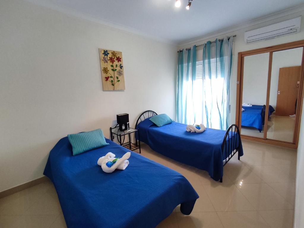 duas camas num quarto com lençóis azuis em T-3 Frente Mar lote19- Casas & Papeis em Armação de Pêra