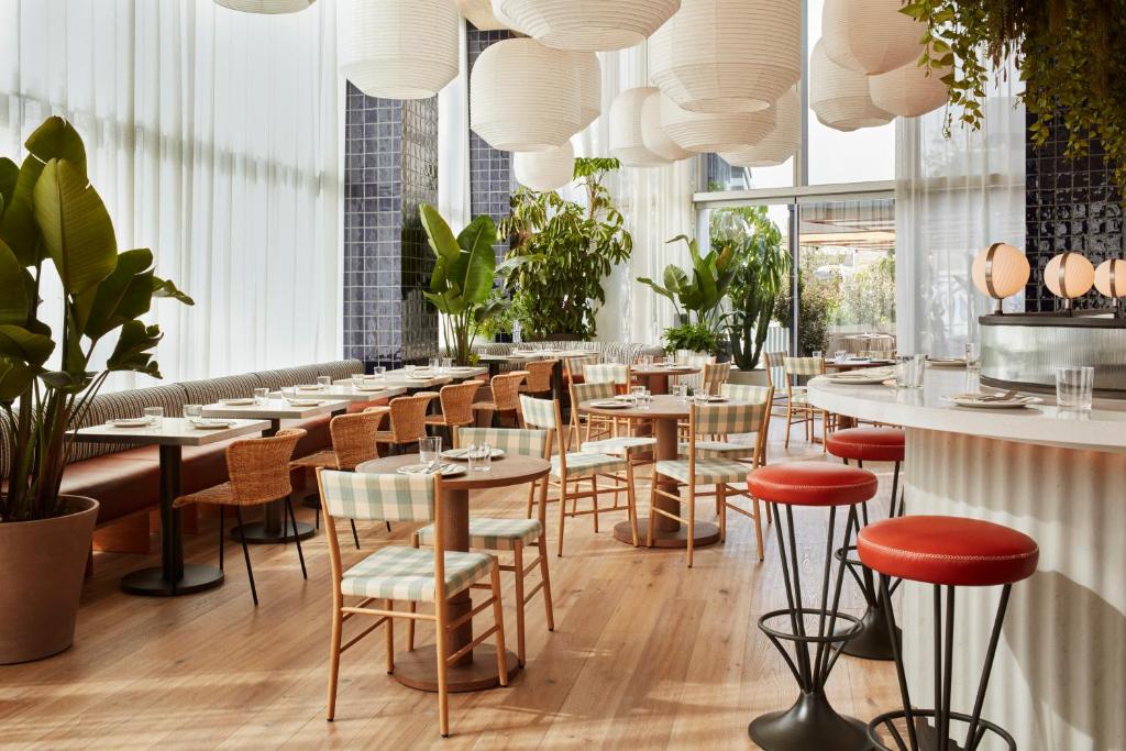 a restaurant with tables and chairs and potted plants at The Hoxton, Poblenou in Barcelona