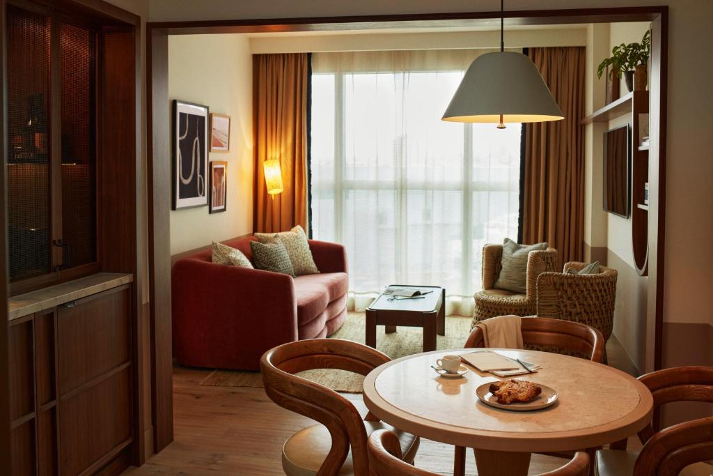 a living room with a table and chairs in a room at The Hoxton, Poblenou in Barcelona