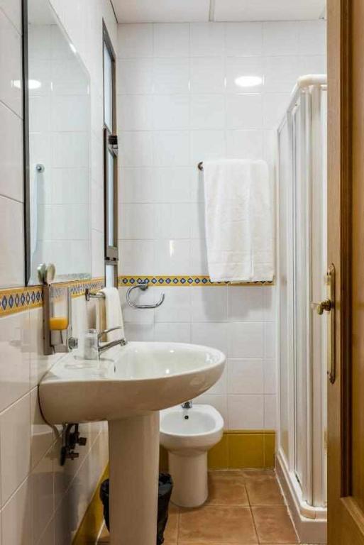 Un baño blanco con lavabo e inodoro. en KubiK HOTEL, en Cáceres