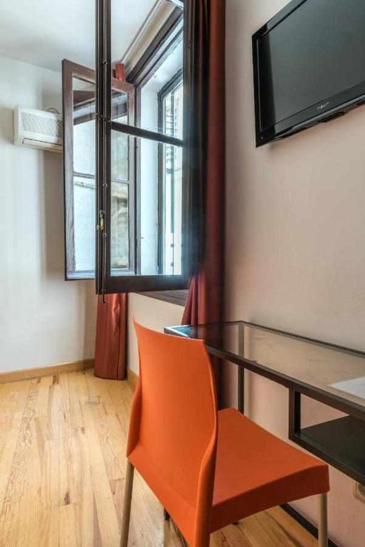 comedor con mesa de cristal y silla naranja en KubiK HOTEL, en Cáceres