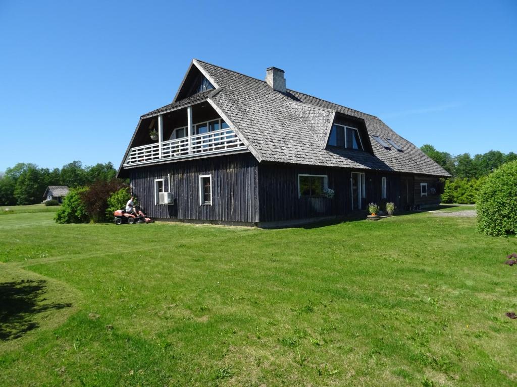 a large black barn on a grass field at Tiiupesa Guest House in Hellamaa