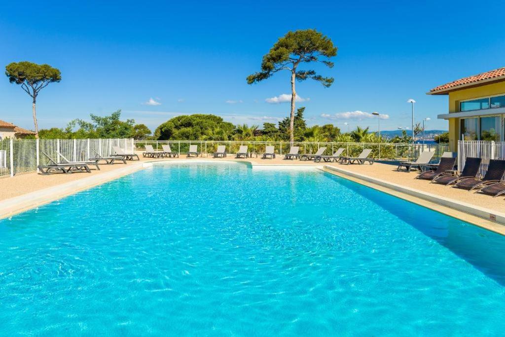 a swimming pool with blue water and chairs at A 500 mètres des plages et du port du brusc, Les terrasses des embiez avec piscine et spa in Six-Fours-les-Plages