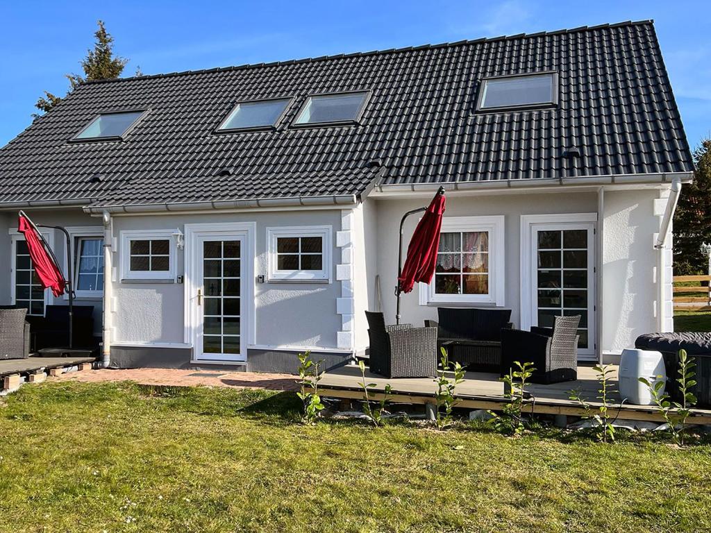 una casa blanca con banderas rojas delante de ella en Ferienhäuser Insel Usedom Haus Diego 9 - Blick aufs Achterwasser! Whirlpool und Sauna en Lütow