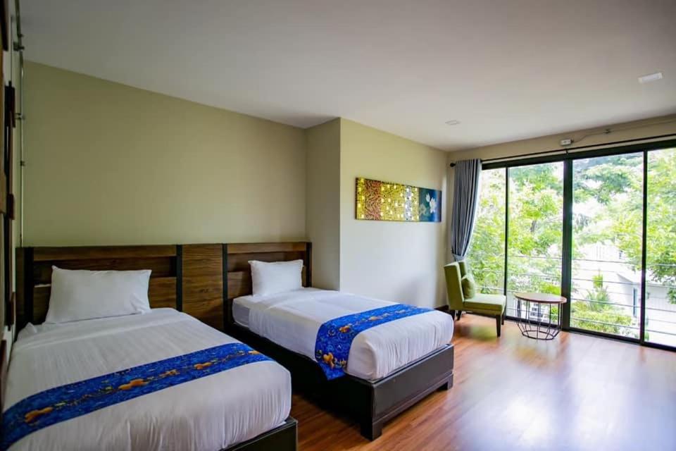 a bedroom with two beds and a large window at Tolopoti Hotel&Resort in U Thong