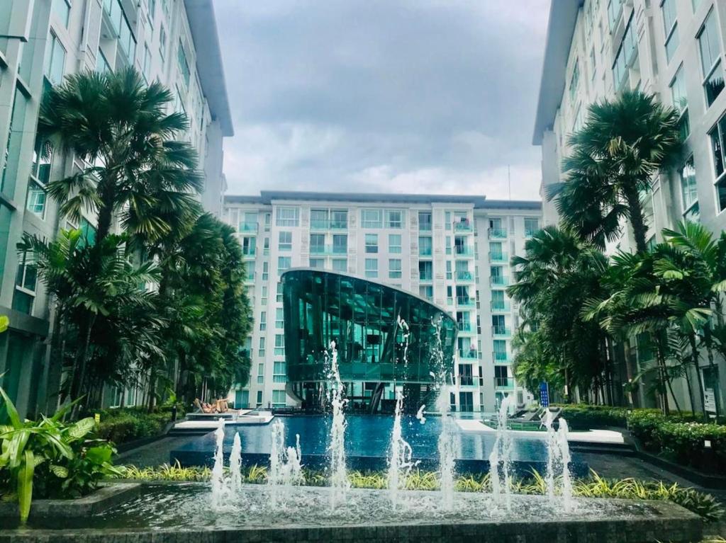 une fontaine en face d'un bâtiment avec des palmiers dans l'établissement City Center Residence Condominium Pattaya RJ, à Pattaya