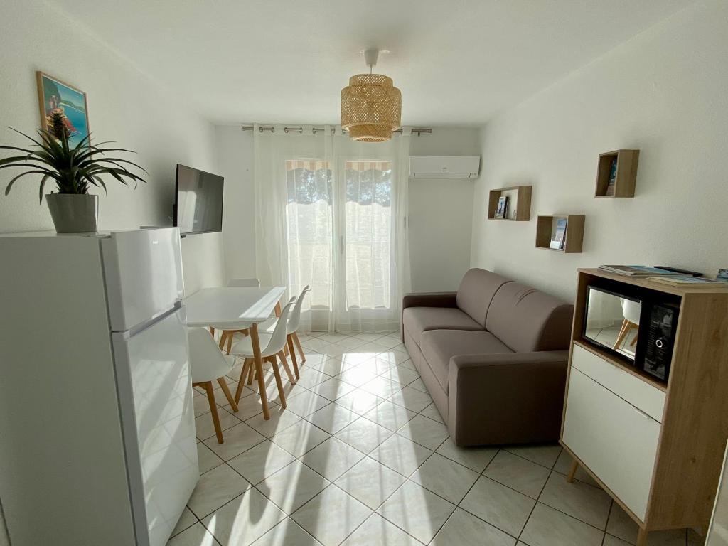 ein Wohnzimmer mit einem Sofa und einem Tisch in der Unterkunft Les locations Cinaureva « Village de la mer » in La Londe-les-Maures