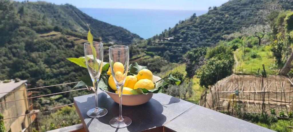 un bol de fruta sentado en una cornisa con dos copas de vino en ☆ Terrace & Relax ☆ CASA FRANCESCHIN_ HOMY 5 TERRE, en Riomaggiore